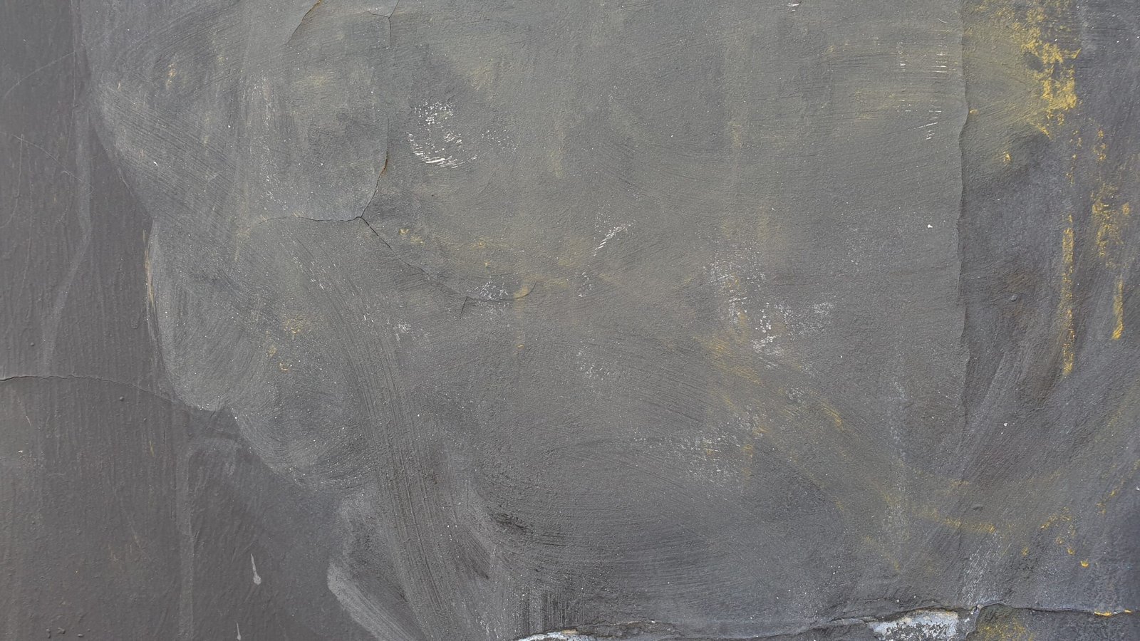 Rough gray wall texture with grungy appearance and yellow stains.